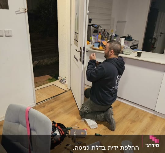 מנעולן מתקין מנעול חדש בדלת כניסה עם כלים על הרצפה